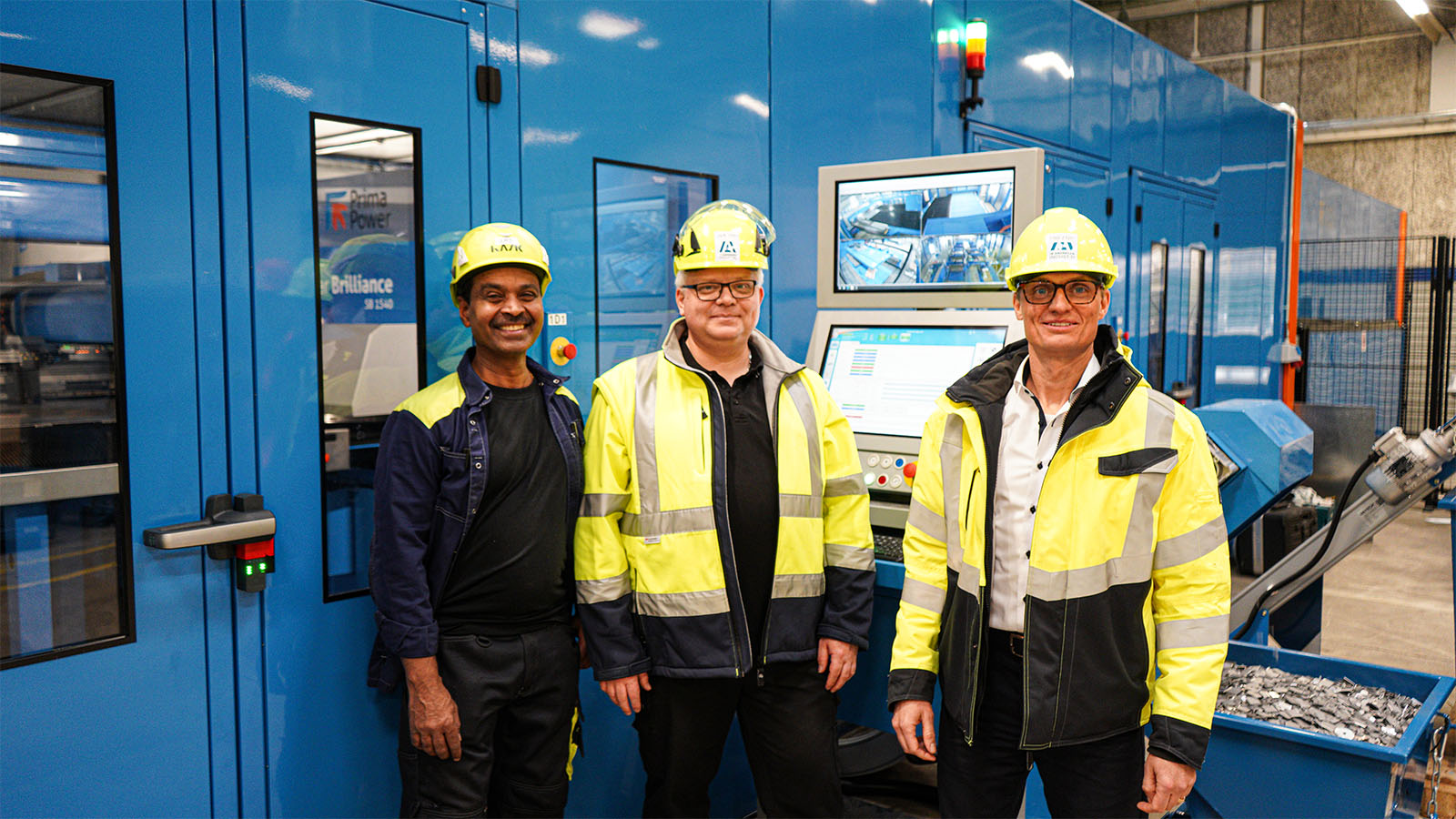 Three employees stand in front of Ib Andresen Industri's new punching centre.