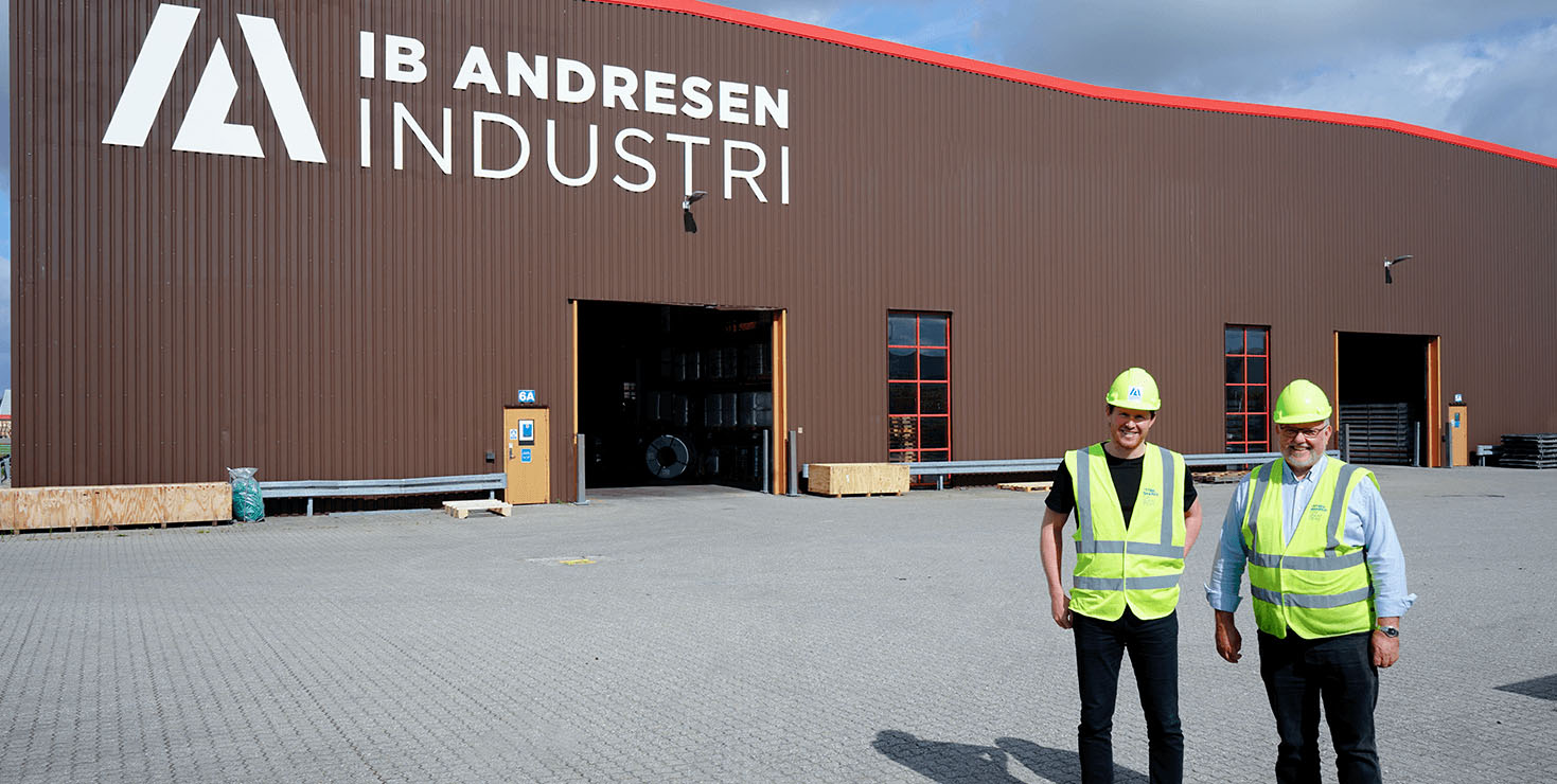 Two emplouees standing in front of a building with a Ib Andresen Industri logo
